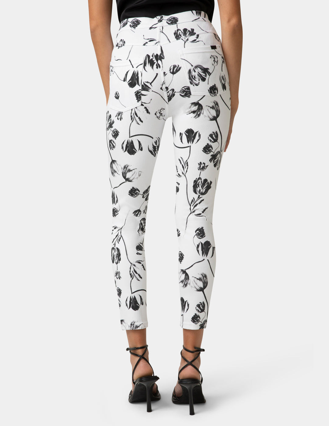 White pants with black floral pattern worn by a person on a white background