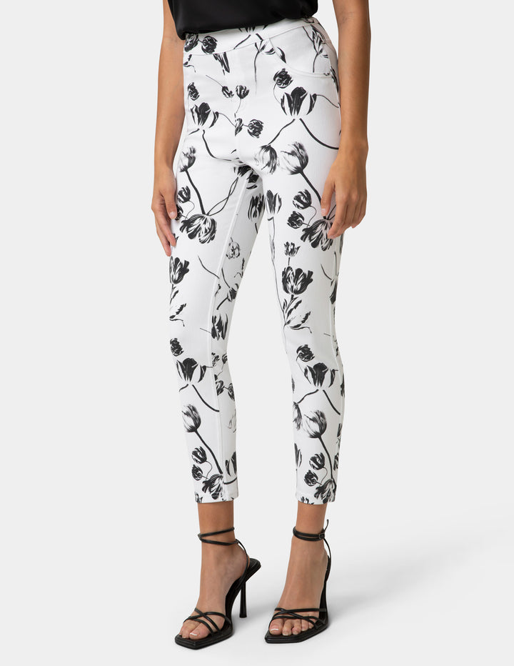 White pants with black floral pattern worn by a person on a white background