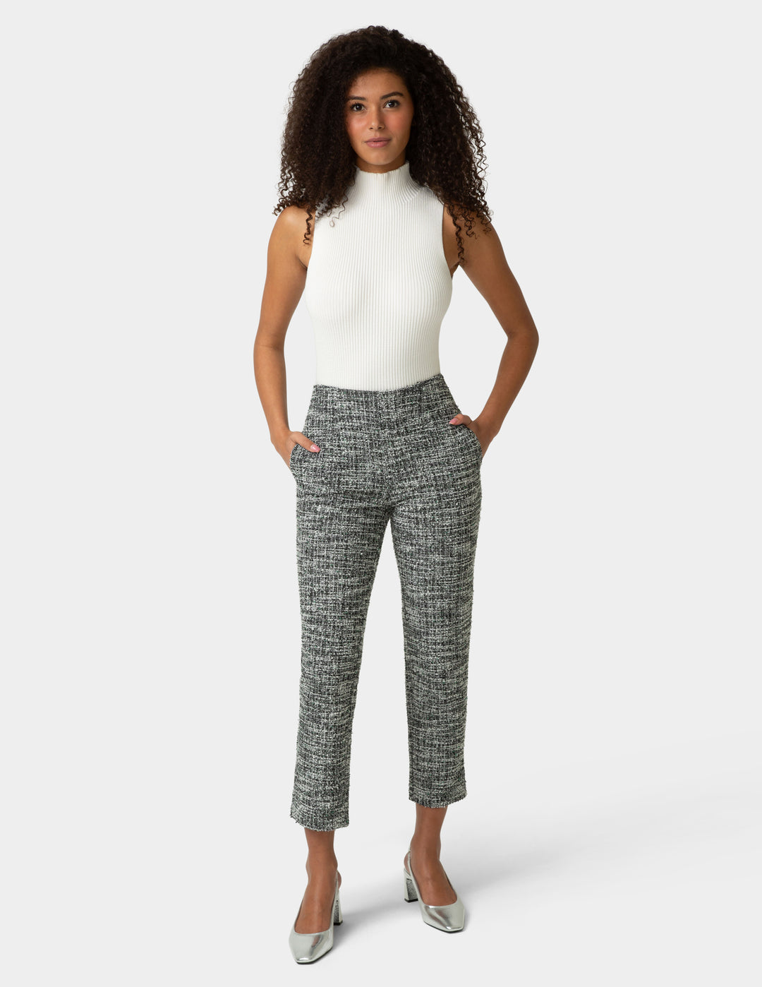 Woman wearing a white top and patterned pants on a white background