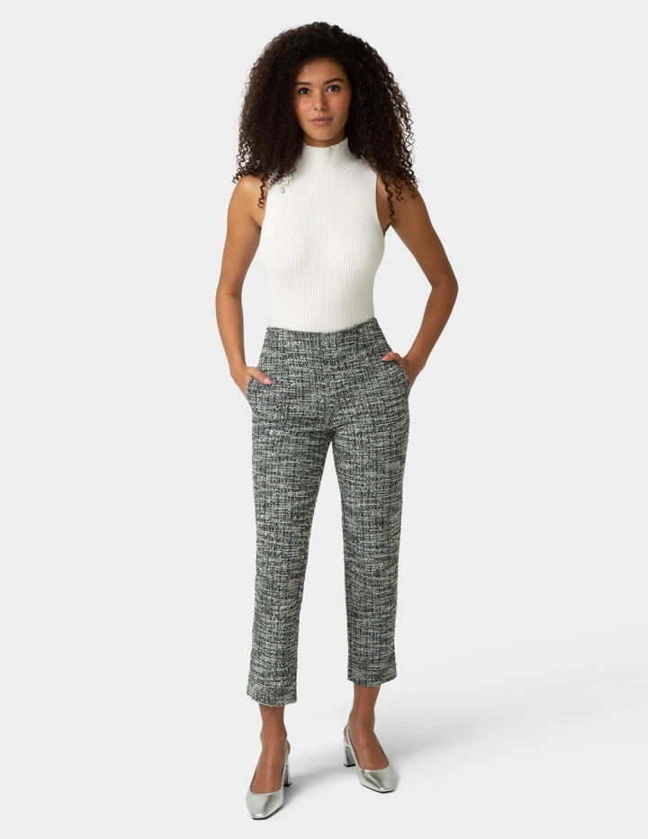Woman wearing a white top and patterned pants on a white background