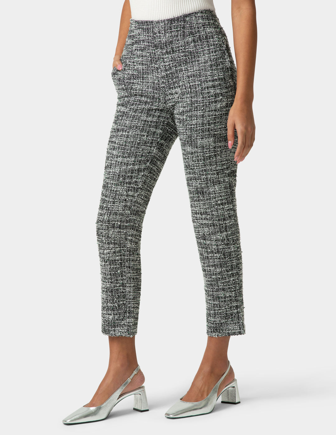 Person wearing black and white patterned pants with silver shoes on a white background