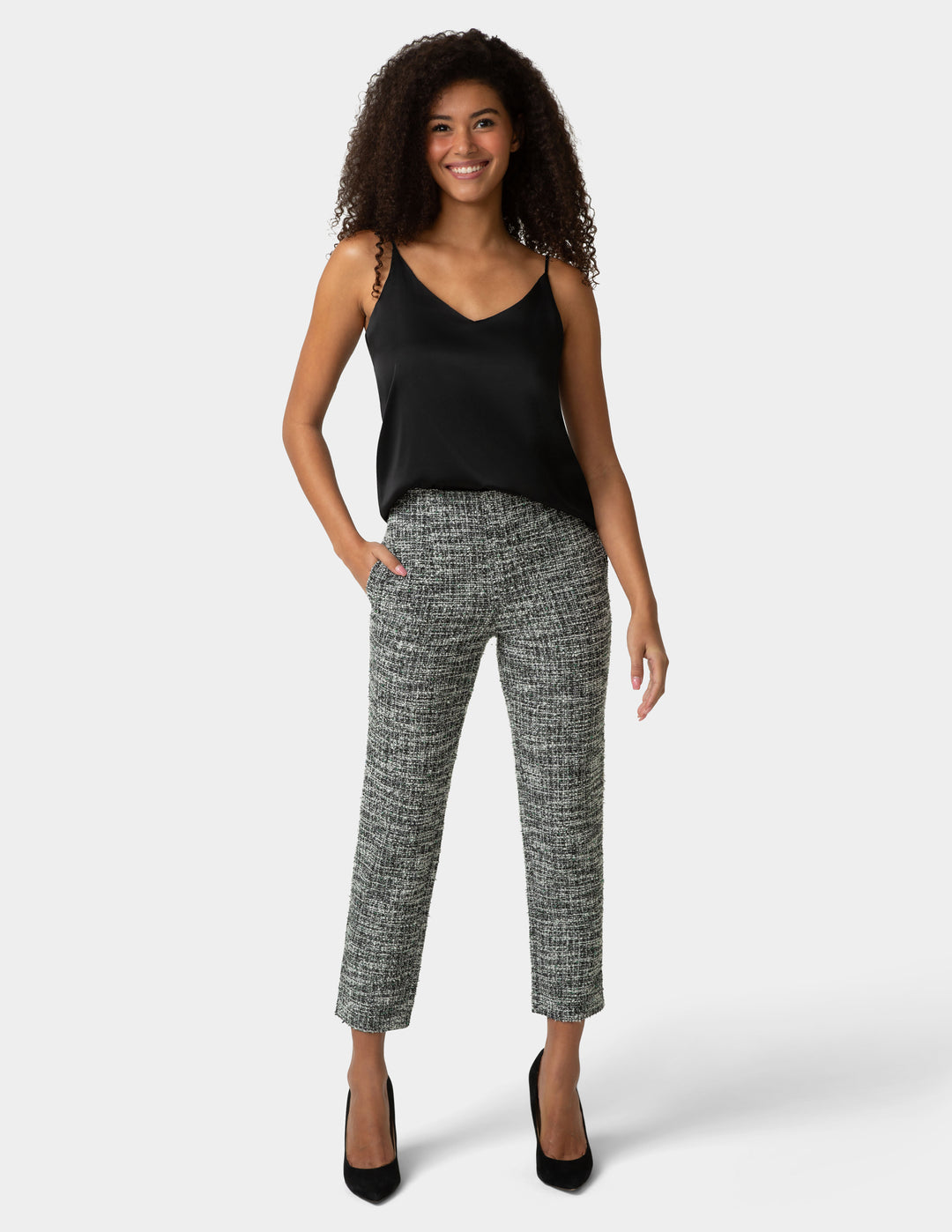 Woman wearing a black sleeveless top and patterned pants on a white background