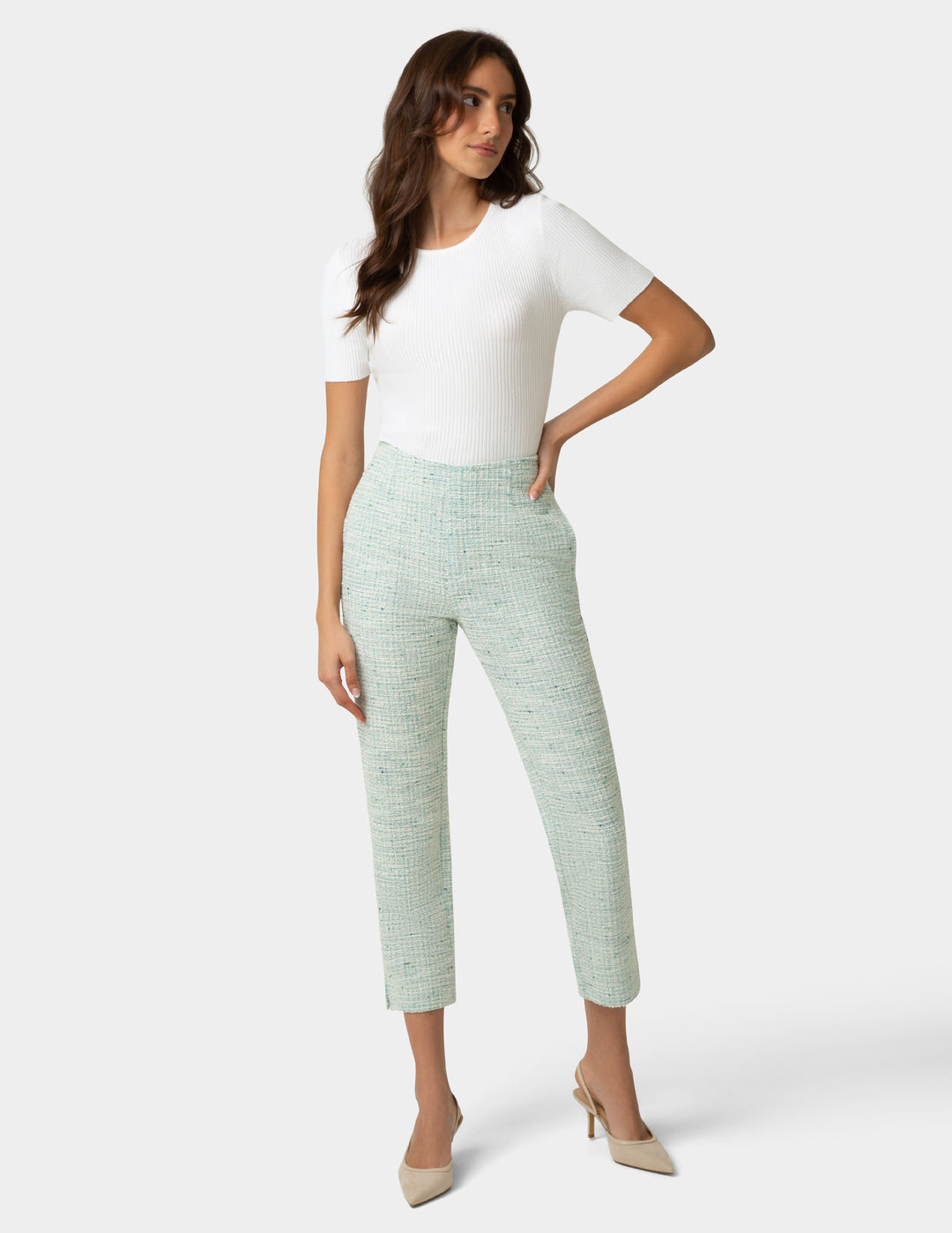 Woman wearing a white top and mint green textured pants on a white background