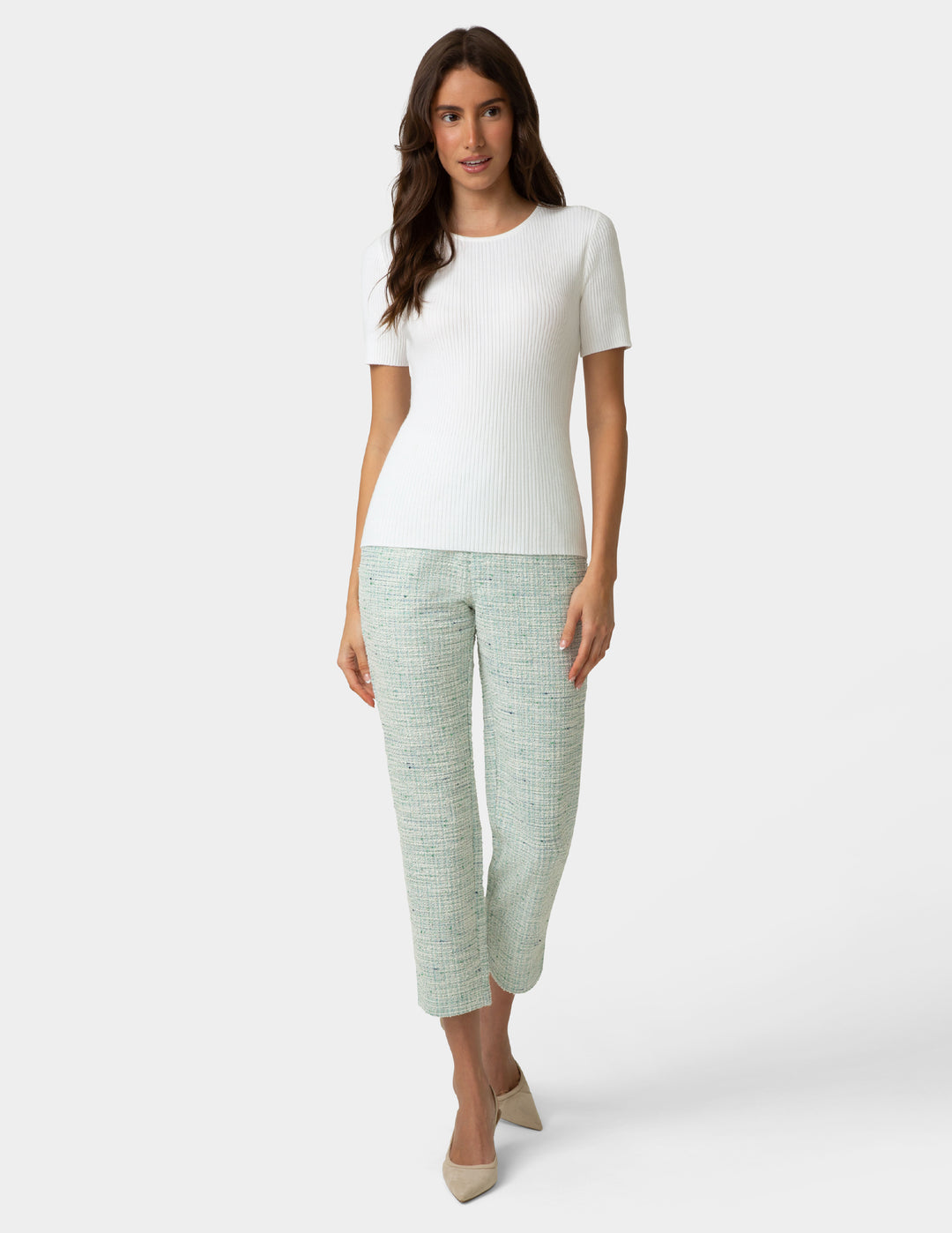 Woman wearing a white top and mint green textured pants on a white background