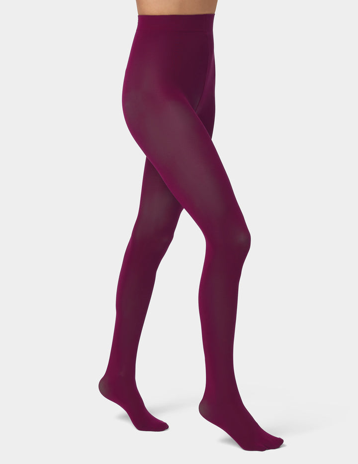 A model's legs wearing sheer, high-waisted tights in an eggplant color, shown from the waist down against a light gray studio background.